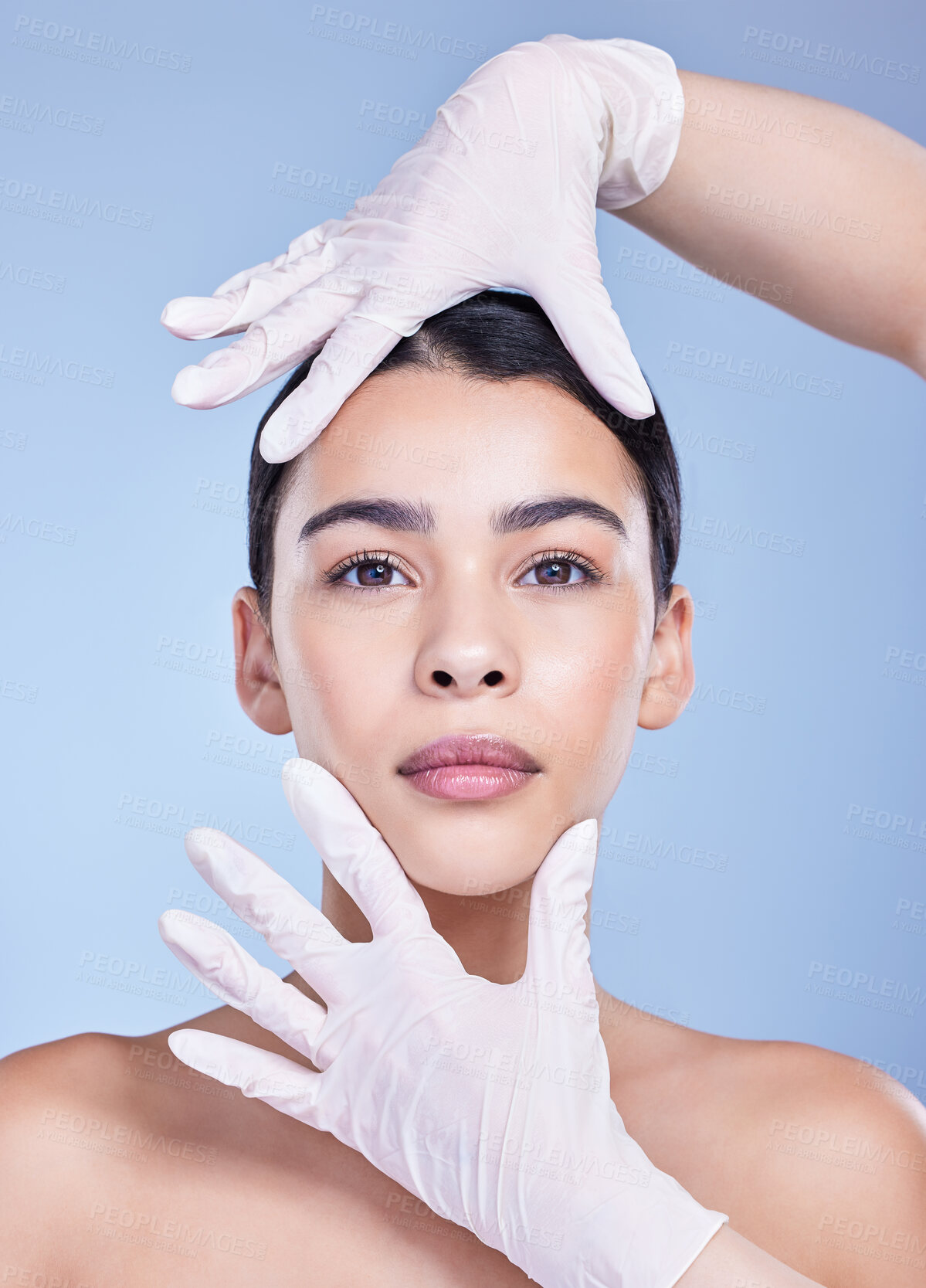 Buy stock photo Woman, portrait and plastic surgery with gloves for facial transformation on a blue studio background. Face of young female person with hands of medical surgeon in beauty makeover, change or skincare