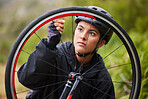 One athletic young woman fixing the wheel of a bike while cycling outdoors. Sporty female wearing helmet and checking the air pressure of a bicycle tyre for repairs while riding outside for exercise 