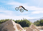 Young man showing his cycling skills while out cycling on a bicycle outside. Adrenaline junkie practicing a dirt jump outdoors. Male wearing a helmet doing extreme sports with a mountain bike