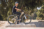 Portrait of a handsome man wearing a helmet and taking a break from cycling on his bicycle outside. Male athlete exercising in a park. Sporty male training on his bike. Keeping his heart healthy