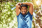 Fit athletic mixed race man smiling while stretching during a workout at the park. Young hispanic man doing warm up exercises outdoors on a sunny day. Dedicated to fitness and a healthy lifestyle