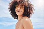 Portrait of young trendy beautiful mixed race woman with an afro smiling and posing alone outside. Hispanic woman wearing sunglasses and feeling happy. Fashionable African American woman in the city