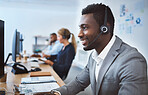 Happy young african american call centre telemarketing agent talking on a headset while working on computer in an office. Confident friendly male consultant operating helpdesk for customer service and sales support