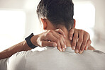 One mixed race man from behind holding his sore neck while exercising in a gym. Guy suffering with painful injury from fractured joint and inflamed muscles during workout. Struggling with stiff body cramps causing discomfort and strain