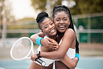 Portrait of two friends hugging after a match. Cheerful young girls embracing after a game of tennis. African american women being affectionate after a tennis match. Happy friends on a tennis court