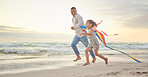 Cute little girl and her mixed race dad flying a kite on the beach. Adorable daughter and her handsome father running and playing in the sand next to the sea at sunset. Family bonding and happiness