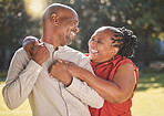 Happy affectionate mature african american couple sharing an intimate moment outside at the park during summer. In love seniors smiling and embracing while spending quality time together outdoors