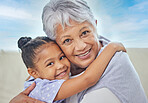 Smiling adorable little mixed race girl hugging her grandmother while bonding with her at home. Beautiful hispanic mature woman showing love and affection to her granddaughter in the living room