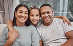 Happy and affectionate young mixed race family of three sitting on a sofa in the living room at home. Married couple sitting with their cute little girl in the lounge. Mom, dad and adorable daughter