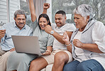 Happy and affectionate mixed race family of four using a laptop to watch sports and cheer on their favourite team in the home living room. Married couple sitting with their mature parents on the sofa