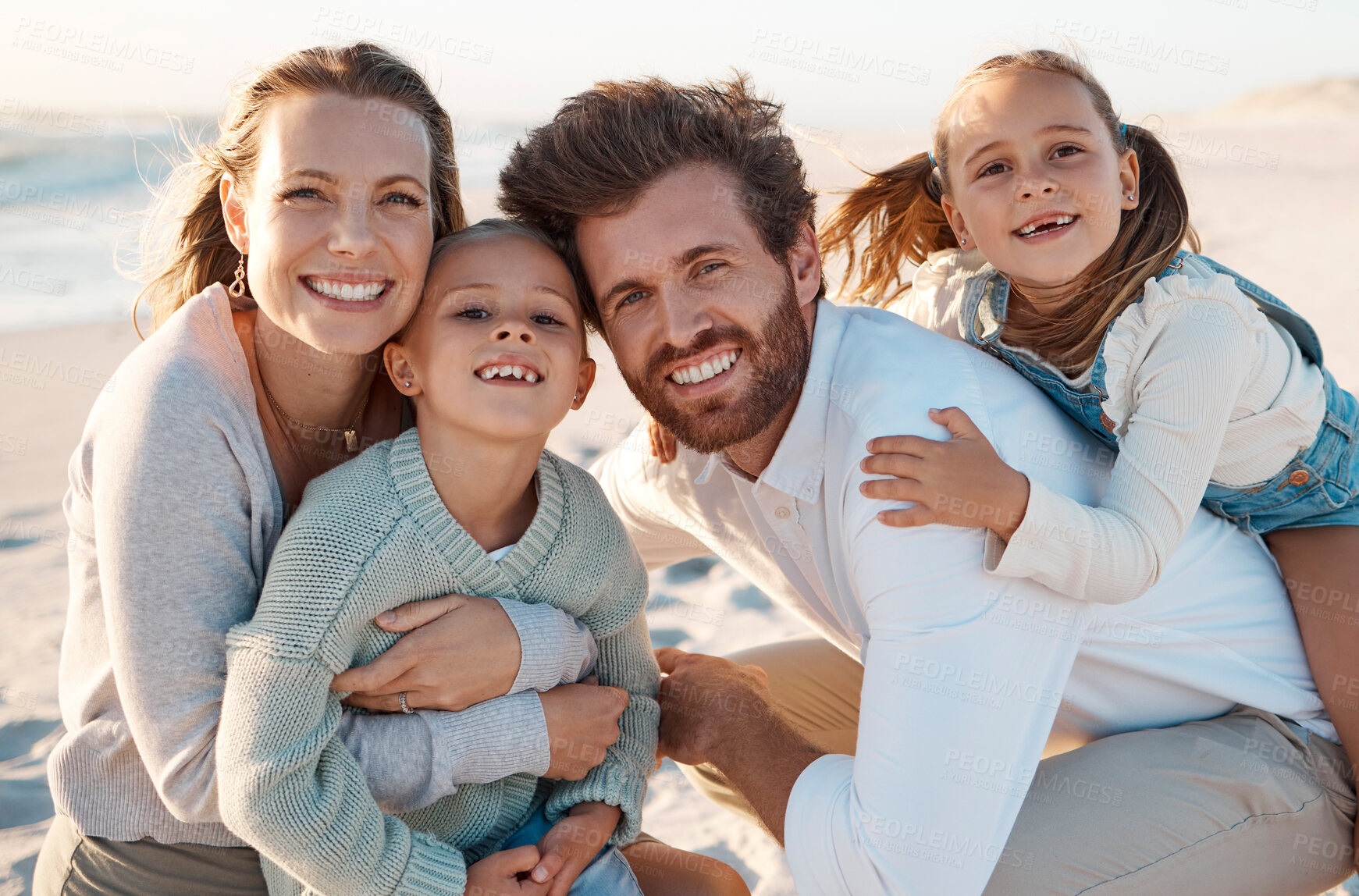 Buy stock photo Parents, children and hug at beach, portrait and smile with care, love or bonding on holiday in summer. Father, mother and daughter kids for embrace, happy or connection in sunshine by ocean in Spain