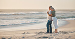 Mature couple enjoying the view on the beach. Senior couple bonding on holiday by the beach. Senior couple being affectionate by the ocean. Mature wife hugging her husband on the beach