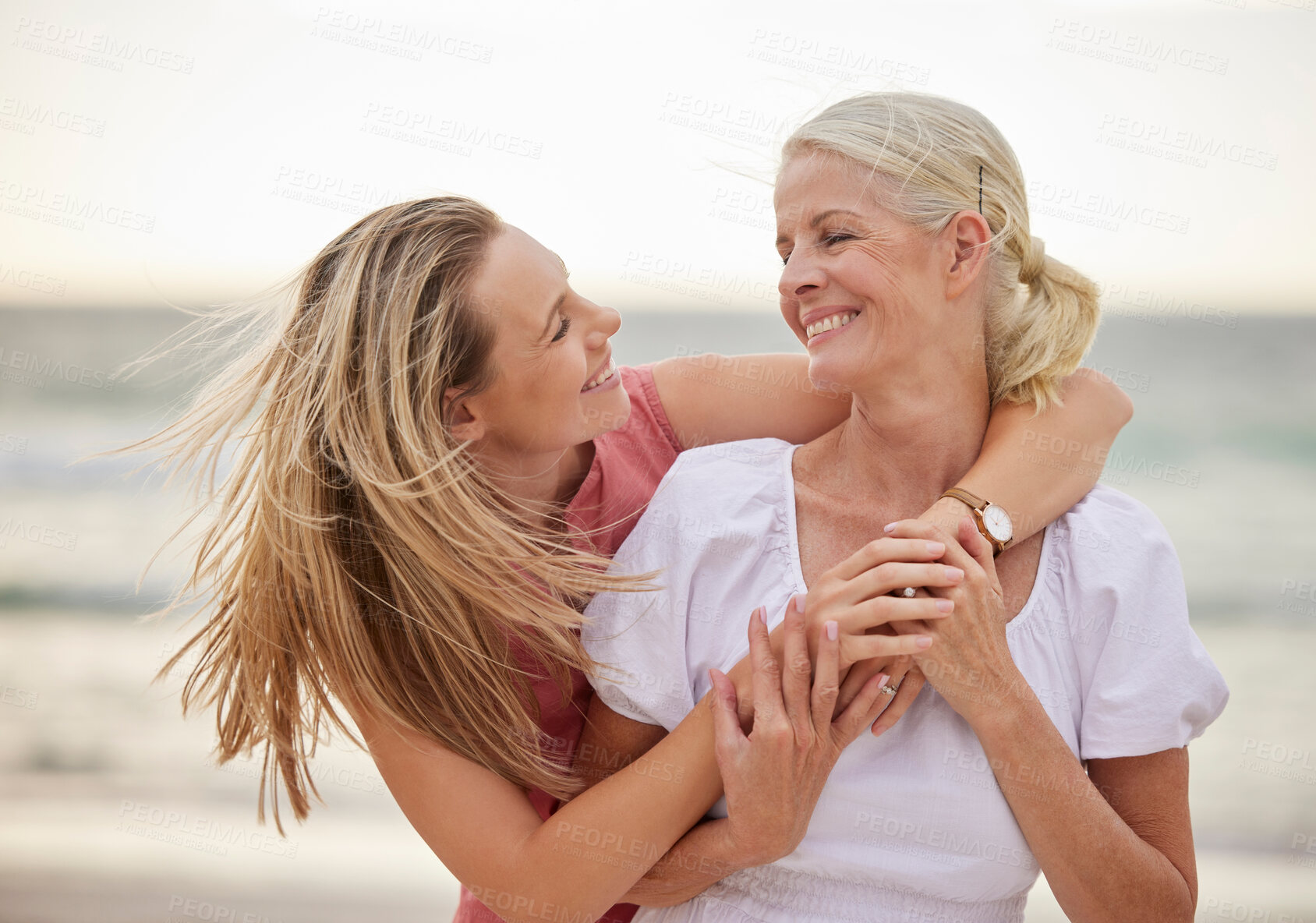 Buy stock photo Hug, beach and senior mom with daughter for bonding holiday, love and embrace on weekend travel. Nature, mother and woman laughing on ocean adventure together with smile, fun and island vacation.