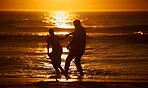 Silhouette affectionate senior couple sharing an intimate moment on the beach. Backlit happy husband and wife enjoying a summer day by the sea. They love spending time together on the coast at sunset