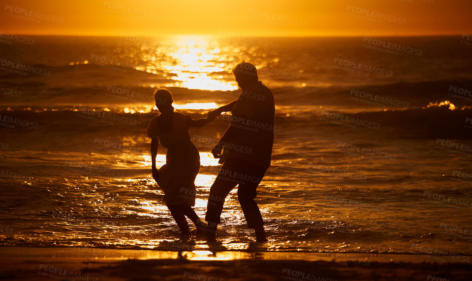 Buy stock photo Love, beach and silhouette of playful couple at sunset for bonding holiday, fun and tropical travel. Nature, man and woman on romantic ocean date together with waves, orange sky and outdoor vacation