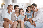 Happy and content hispanic family smiling while relaxing and sitting on the couch together at home. Cheerful and carefree little brother and sister enjoying time with their parents and grandparents