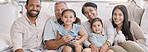 Happy and content hispanic family smiling while relaxing and sitting on the couch together at home. Cheerful and carefree little brother and sister enjoying time with their parents and grandparents