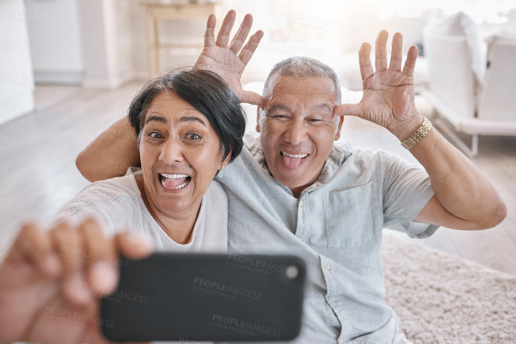 Buy stock photo Senior couple, selfie and crazy in home for love, fun and relax in retirement. Funny, elderly people and comic face in living room for photography, teasing and tech for live stream or video call