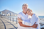 A happy mature caucasian couple enjoying fresh air on vacation at the beach. Smiling retired couple hugging and embracing while bonding outside together