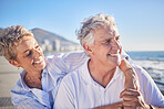 A happy mature caucasian couple enjoying fresh air on vacation at the beach. Smiling retired couple getting a cardio workout while being playful and having fun together on a romantic date