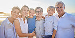 Portrait of a senior caucasian couple at the beach with their children and grandchild. Happy family relaxing on the beach having fun and bonding