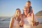 Portrait of a little caucasian girl being carried by her grandpa while her mother walks on the beach during sunset.  Family fun in the summer sun