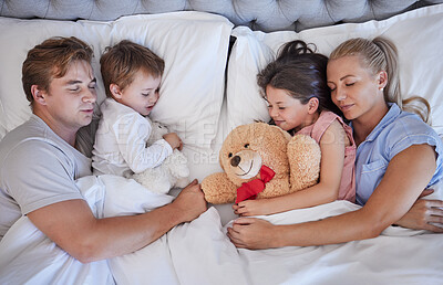 Buy stock photo Above, family and sleeping with love in bedroom for nap, bonding and embrace support of childhood memory. Parents, kids and hug with teddy bear for tired, relax together and morning care at house