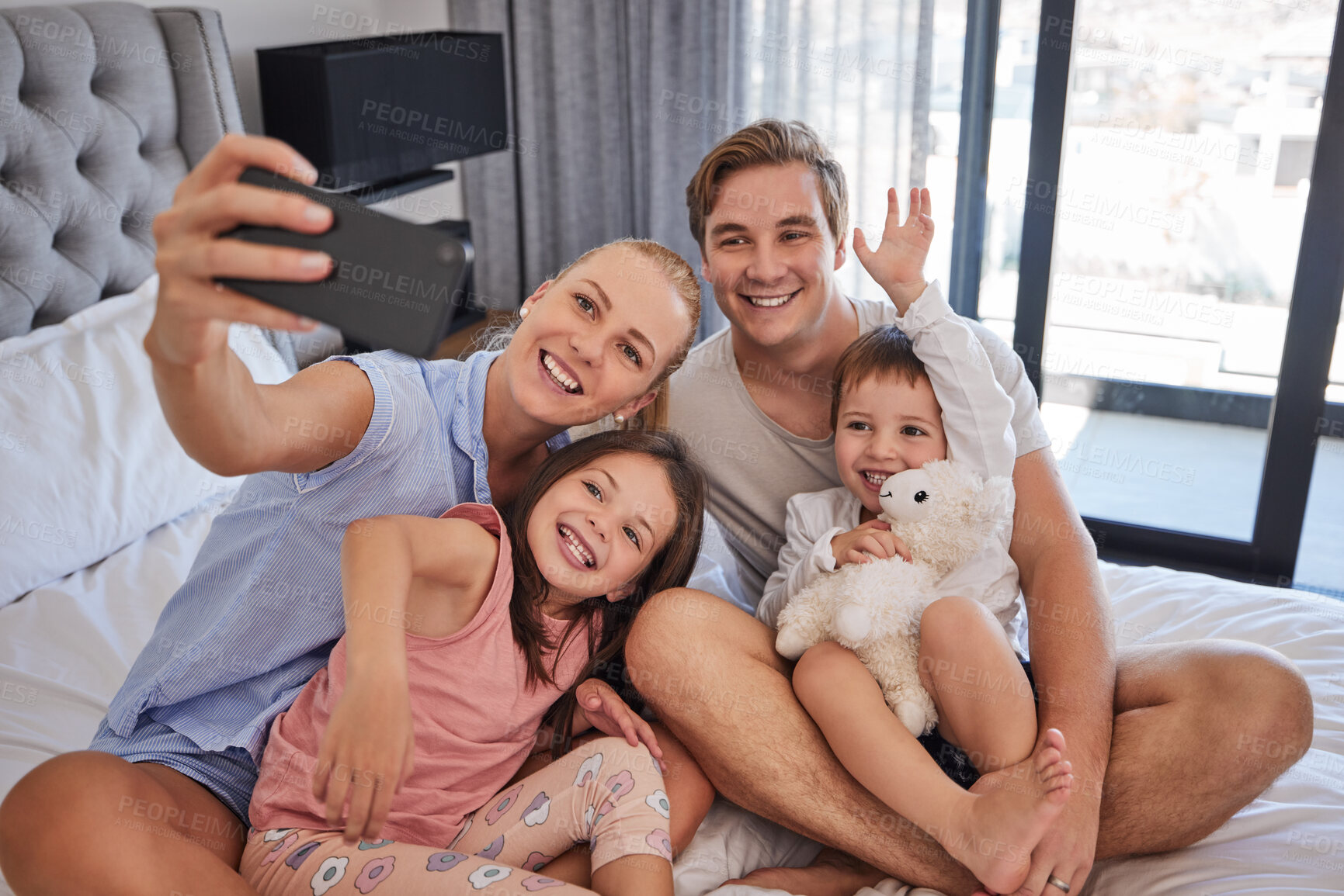 Buy stock photo Happy family, selfie and parents with kids in bedroom for photo, picture and memory. Video call, mom and dad with children for connection, love or people wave for greeting in home with stuffed animal