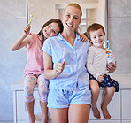 Portrait of happy young caucasian family holding toothbrushes and smiling showing off their healthy teeth. Young mother and her two children getting ready in the morning and brushing their teeth