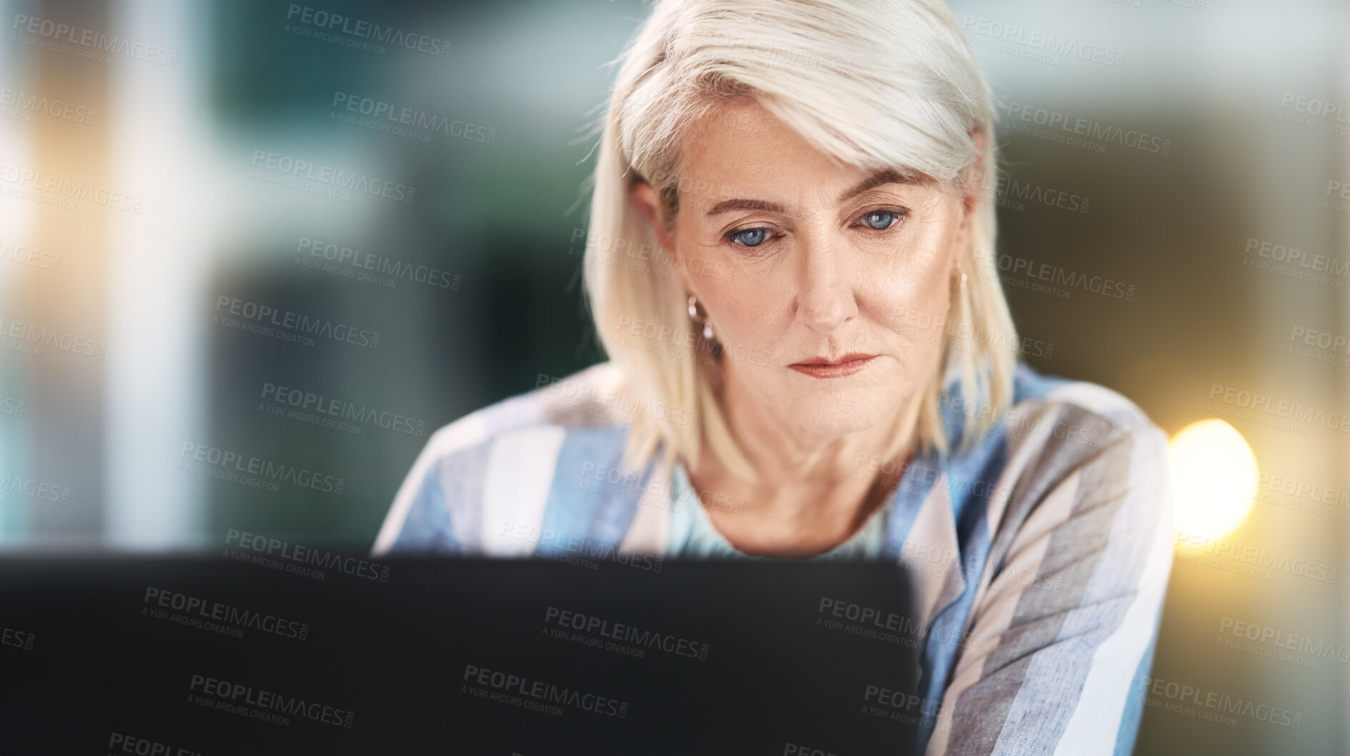 Buy stock photo Serious, reading and mature woman in office, night and email of feedback, deadline and journalist. Laptop, employee and editor for article in newsroom, online or workaholic with project of story