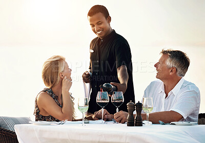 Buy stock photo Shot of a mature couple enjoying a romantic dinner on the beach