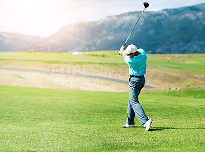 Buy stock photo A young, fit male golfer following through after driving his ball down the fairway