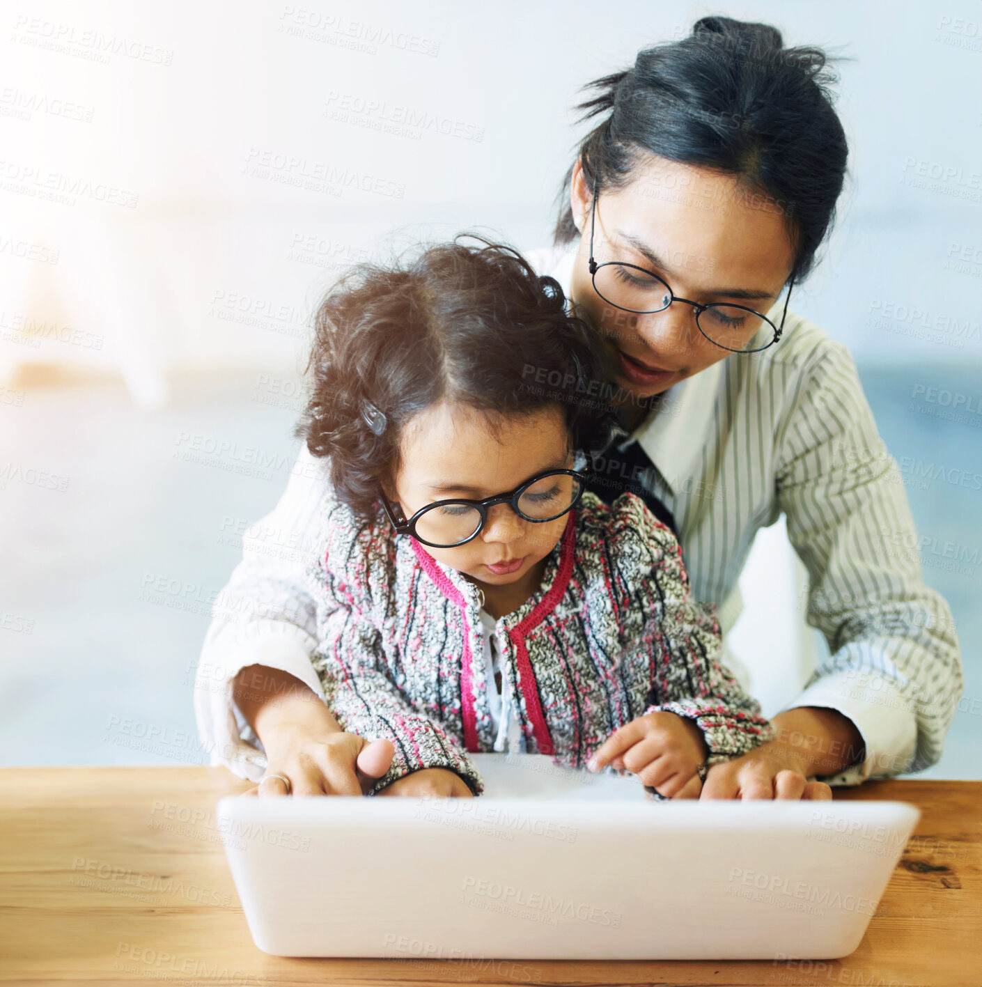 Buy stock photo A cute little girl sitting on her mother&amp;#039;s lap while working on the computer