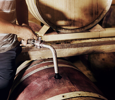 Buy stock photo A man racking a barrel in preparation for bottling wine.  
Closeup of a red wine barrel being refilled with wine by a cellar worker. Winemaker using iron pipe to pour red wine into wooden oak containers