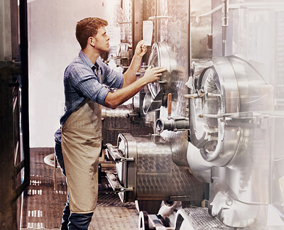 Buy stock photo A young wine maker checking on his vats in the cellar