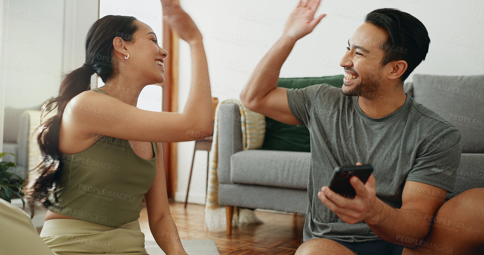 Buy stock photo Happy couple, fitness and high five with phone for success, teamwork or workout goals together at home. Excited man or woman touching hands for winning, achievement or completion of exercise at house