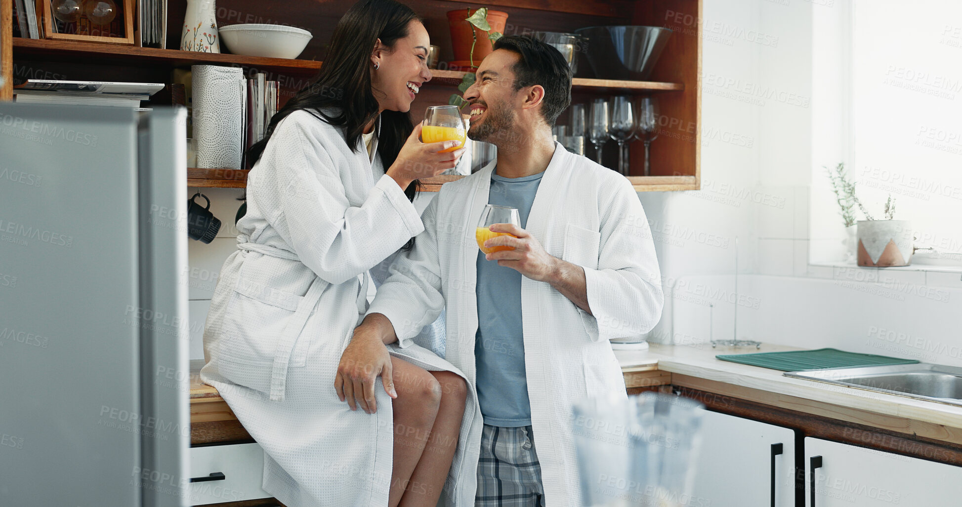 Buy stock photo Couple, smile and love in kitchen with orange juice, happiness and fun in relationship. Man, woman and drink in home for conversation, bonding and relax in morning or excited for anniversary or trust