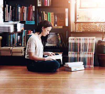 Buy stock photo A young woman sitting on the floor with her legs crossed and reading