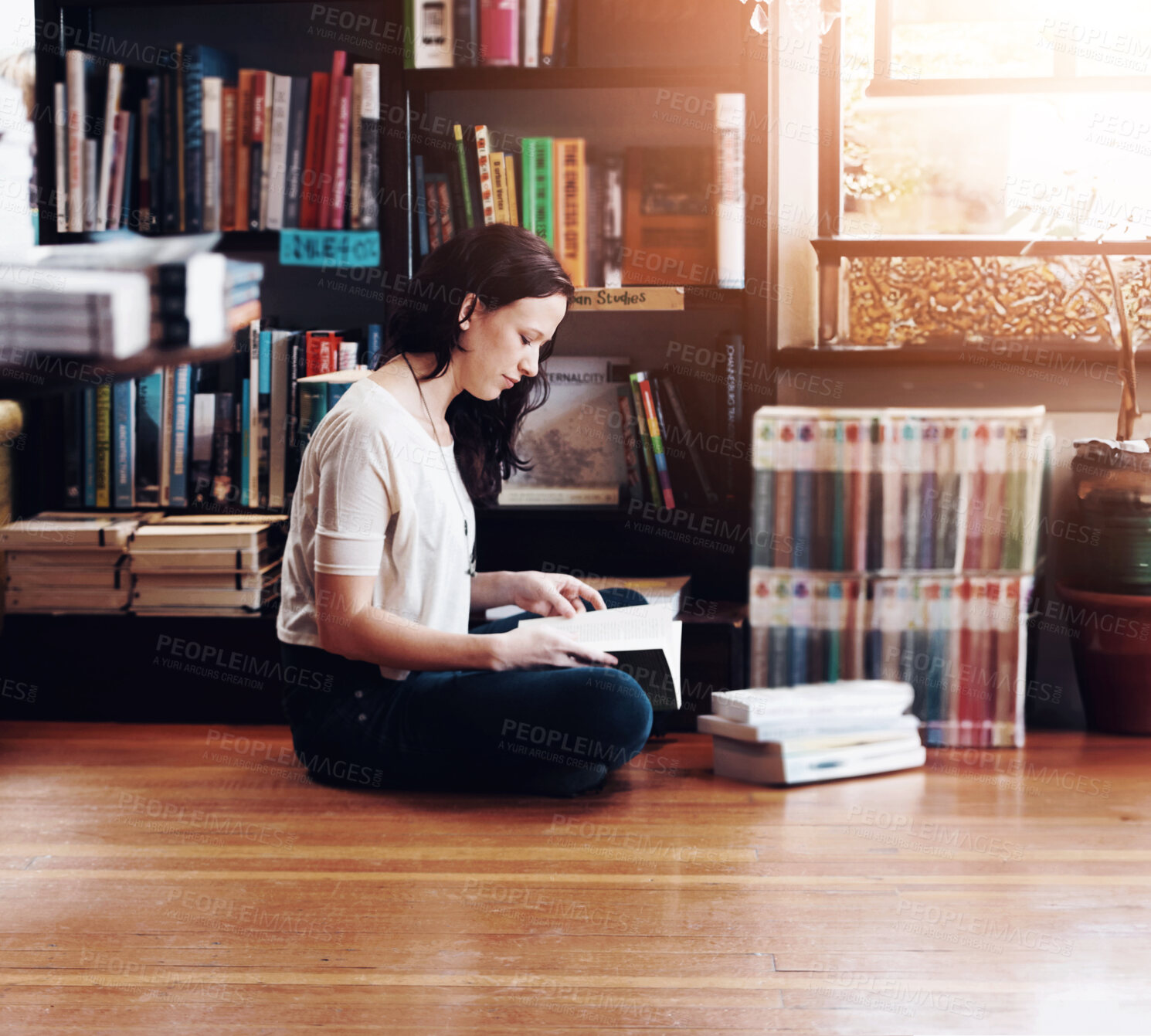 Buy stock photo A young woman sitting on the floor with her legs crossed and reading