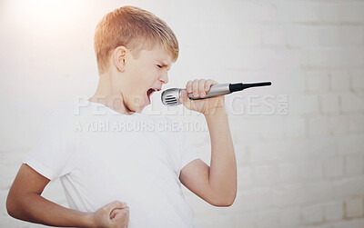 Buy stock photo Young boy lost in song while holding a microphone