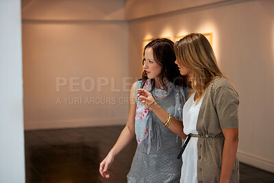 Buy stock photo Two young woman examining a painting up close while attending an exhibition