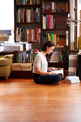 Buy stock photo A young woman sitting on the floor with her legs crossed and reading