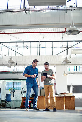 Buy stock photo Shot of two coworkers having a discussion while looking at a digital tablet