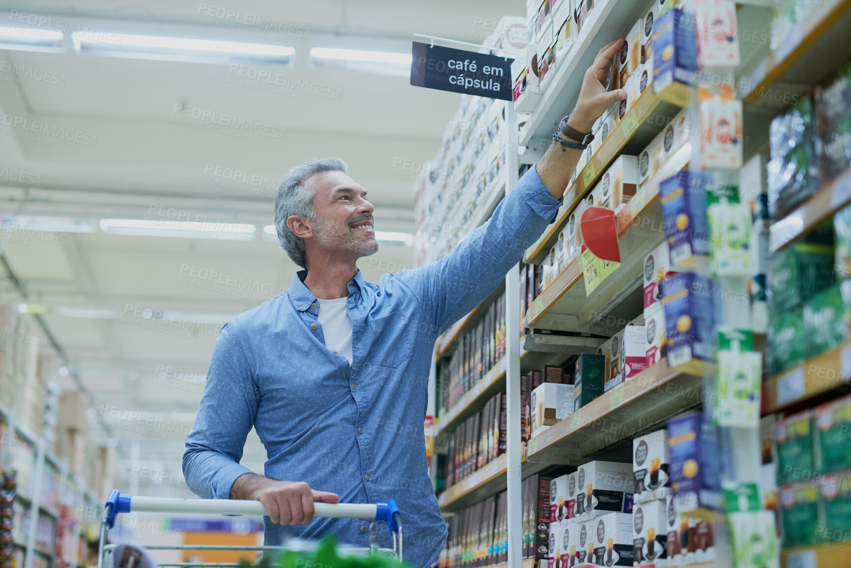 Buy stock photo Happy, shopping and man in supermarket with shelf for food, grocery and products at convenience store. Retail, consumer and person with trolley in aisle for choice, options and discount purchase