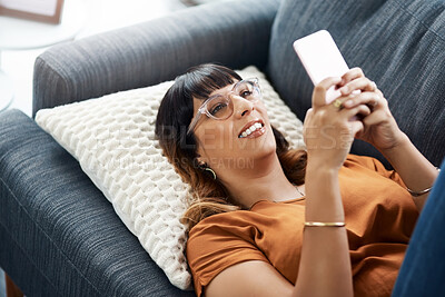 Buy stock photo Above, woman and relax with phone on sofa for communication, social media and reading ebook on website. Smile, female person and rest with mobile for online news, typing email and contact at house