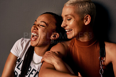 Buy stock photo Cropped shot of two attractive young girlfriends laughing together while sitting against a dark background