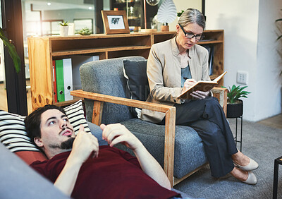 Buy stock photo Shot of a young man having a therapeutic session with a psychologist