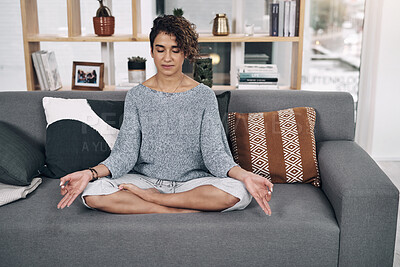 Buy stock photo Shot of an attractive young woman meditating on a sofa at home