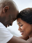 Closeup of a happy young african american couple posing with their foreheads together. Black man and woman smiling and feeling in love. Headshot of loving couple touching heads intimately with bonding