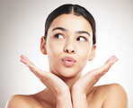 Young happy beautiful mixed race woman pouting and posing against a grey studio background. Face of a carefree hispanic female posing against a background